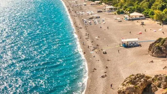Ein langer, geschwungener Sandstrand unterhalb der Berge an der Mittelmeerküste