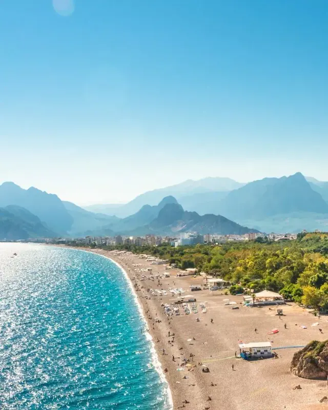 Ein langer, geschwungener Sandstrand unterhalb der Berge an der Mittelmeerküste