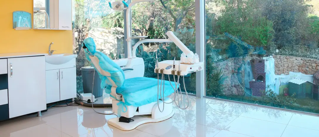 Ein Behandlungsraum bei Dental Art Alanya, der Behandlungsstuhl neben raumhohen Fenstern mit Blick ins Grüne