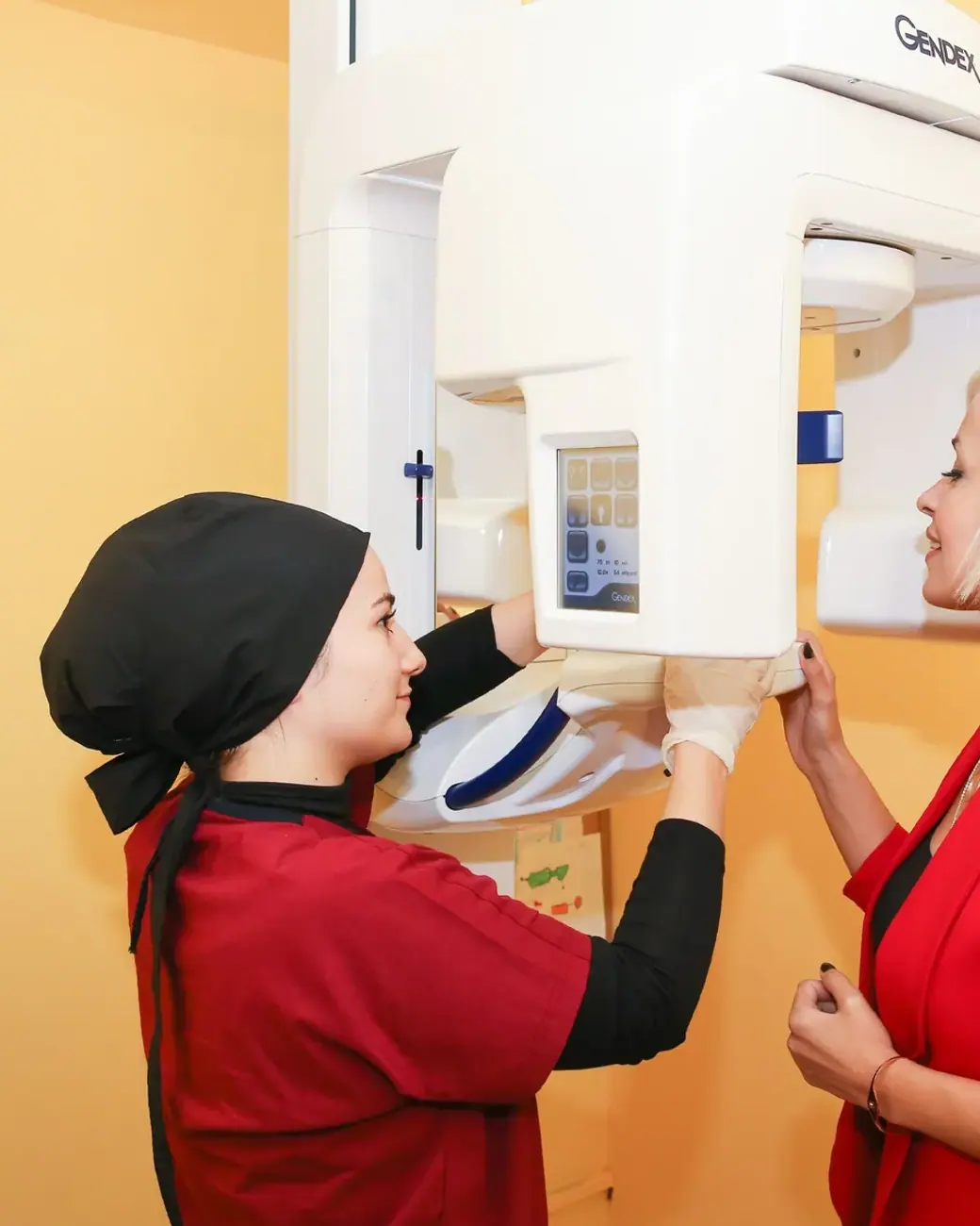 Ein Mitglied des Dental-Art-Teams positioniert eine Patientin am Röntgengerät der Klinik