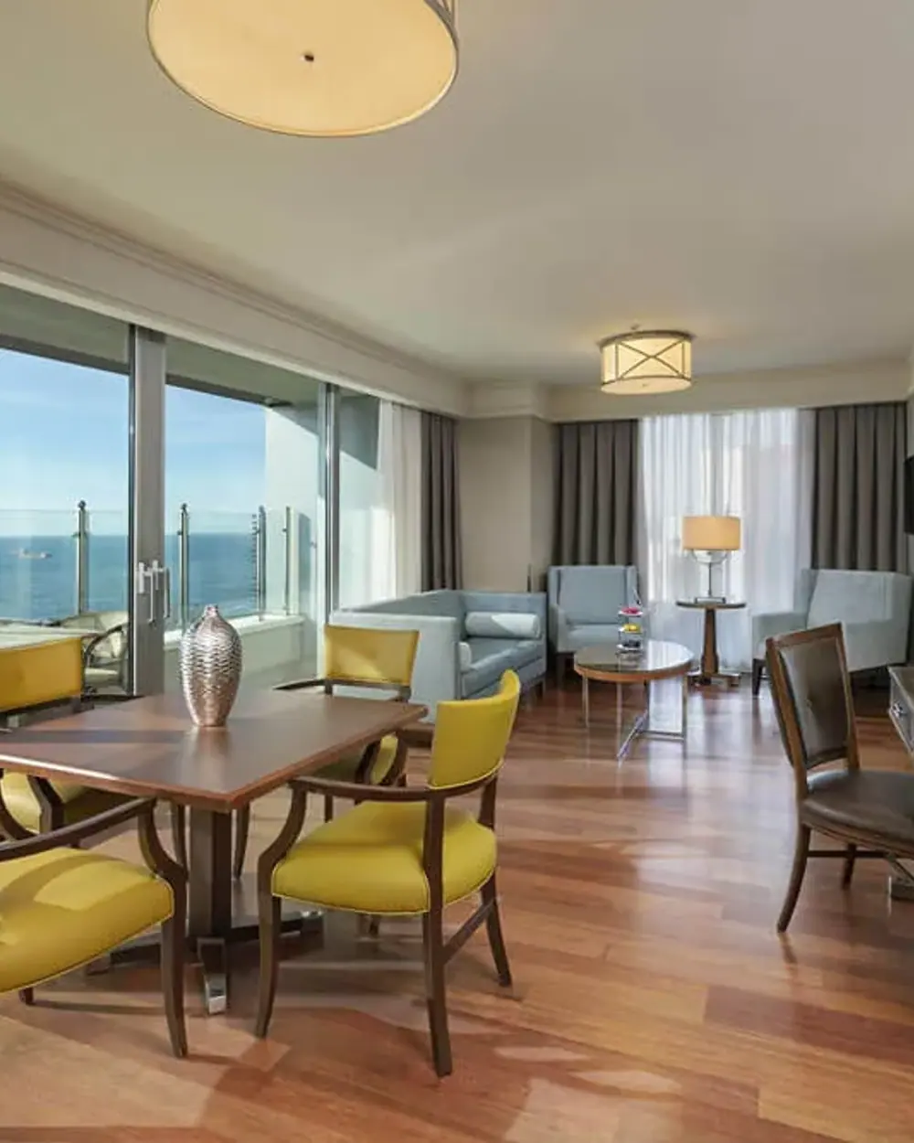 Eine Hotellounge mit Sesseln und hohen Fenstern mit Blick aufs Meer