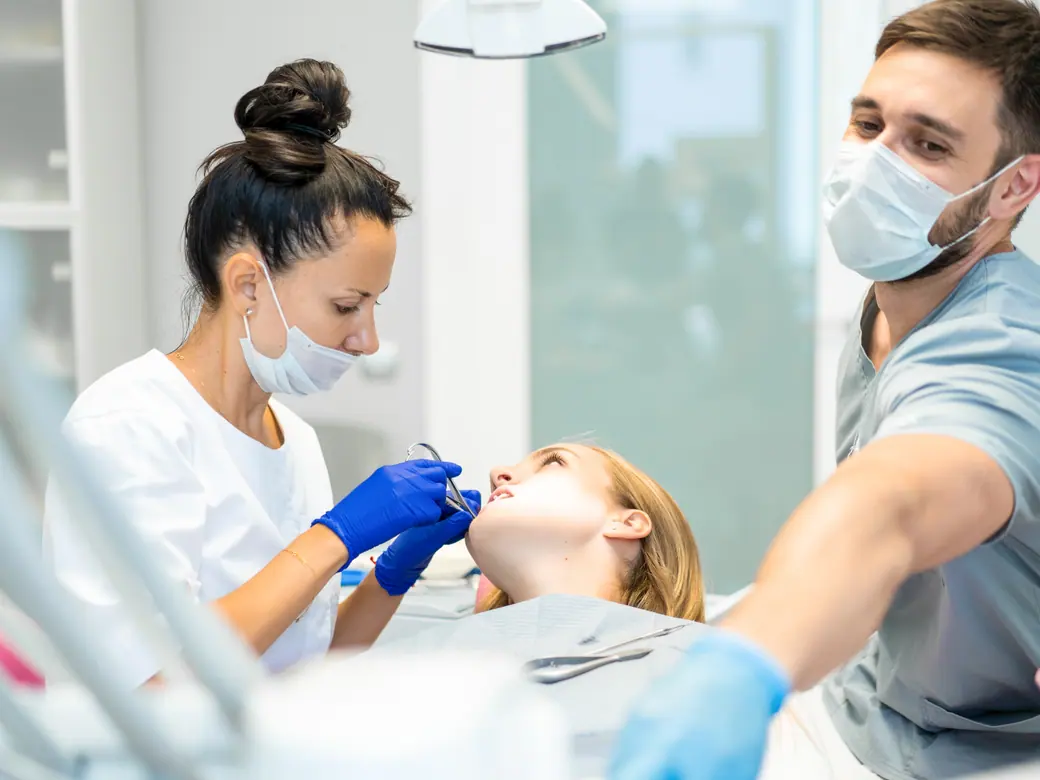 Zwei Fachkräfte arbeiten an einer Patientin, eine hält den Sauger